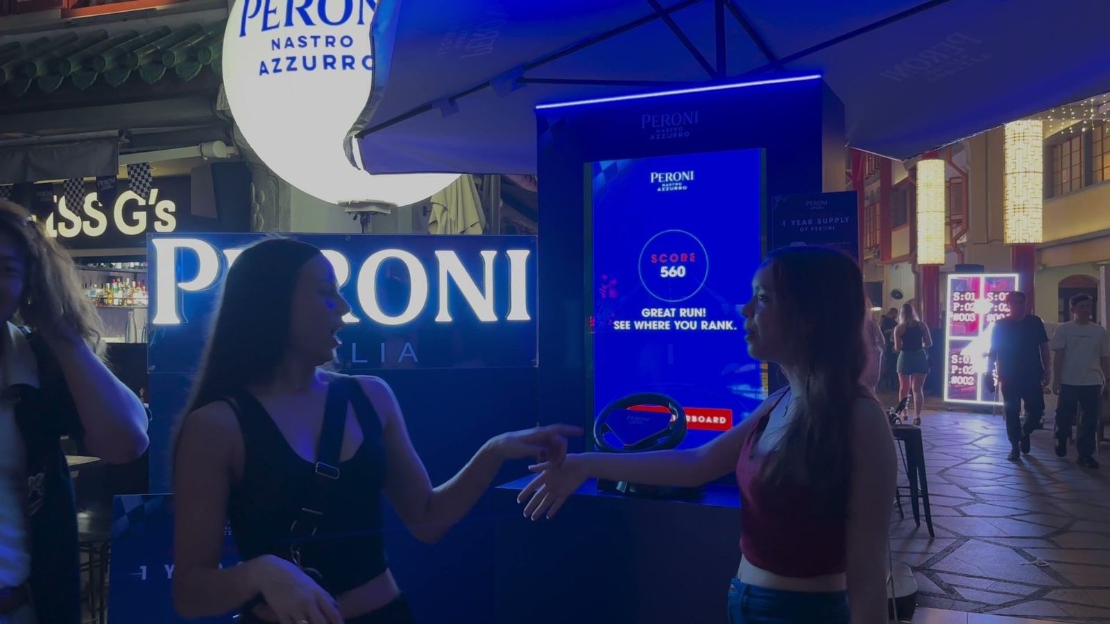 Two friends shaking hands in front of the Speed Collector score screen at the Peroni booth, powered by qiksense