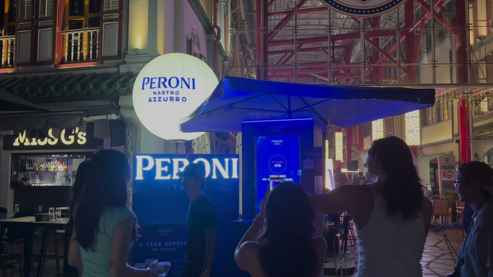 A crowd gathered at the Peroni booth at night to watch a guest play the Speed Collector, run on qiksense