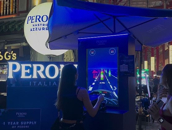 A guest steering the racing wheel at the Speed Collector by Popper Asia for Peroni at Far East Square, with the game run on qiksense
