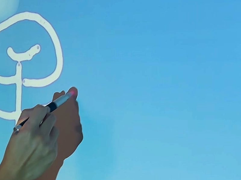 A hand drawing a tree on a sky picture with the IR pen