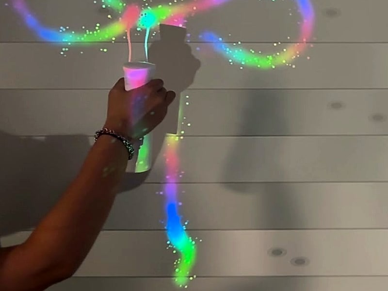 A hand spraying colour onto the wall with the white spray bottle